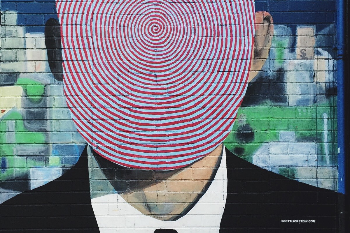 graffiti of man in business suit with red spiral face