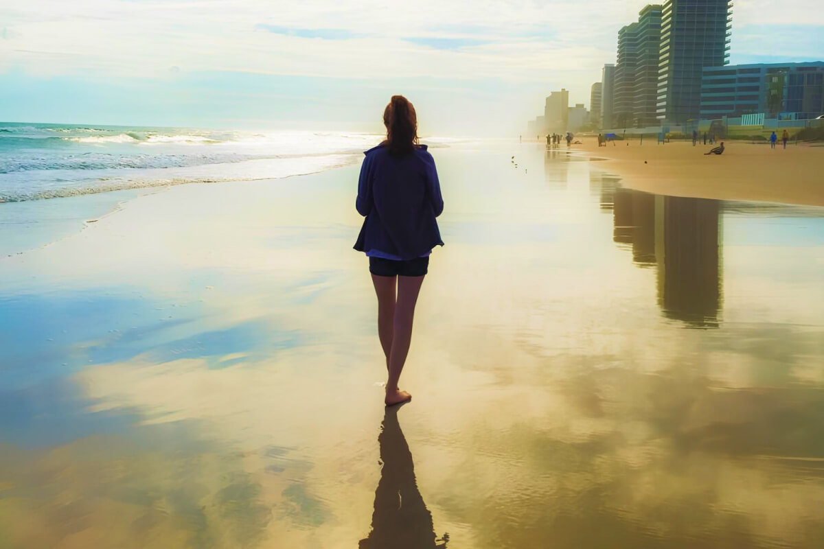 Woman walking on the beach with skyscrapers in the background