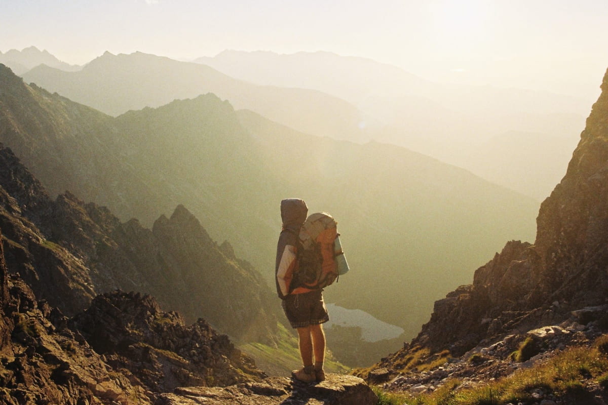 man standing on top of a mountain with a hiking backpack