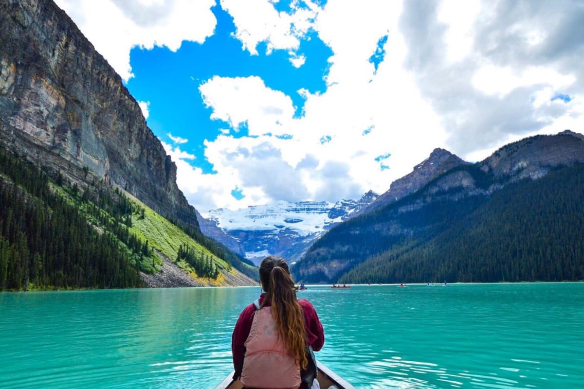 Woman in kayak on a clear blue lake near mountains