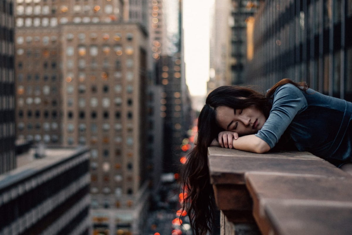 Asian woman sleeping on ledge of city building