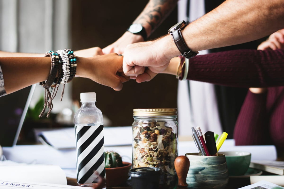 Group of employees fist bumping over desk in an office