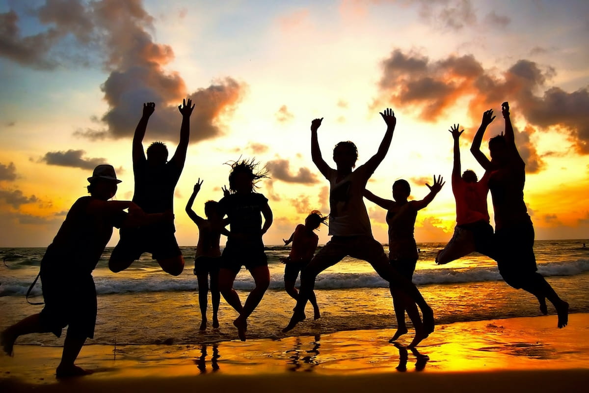 shadow silhouettes of people jumping on beach at sunset