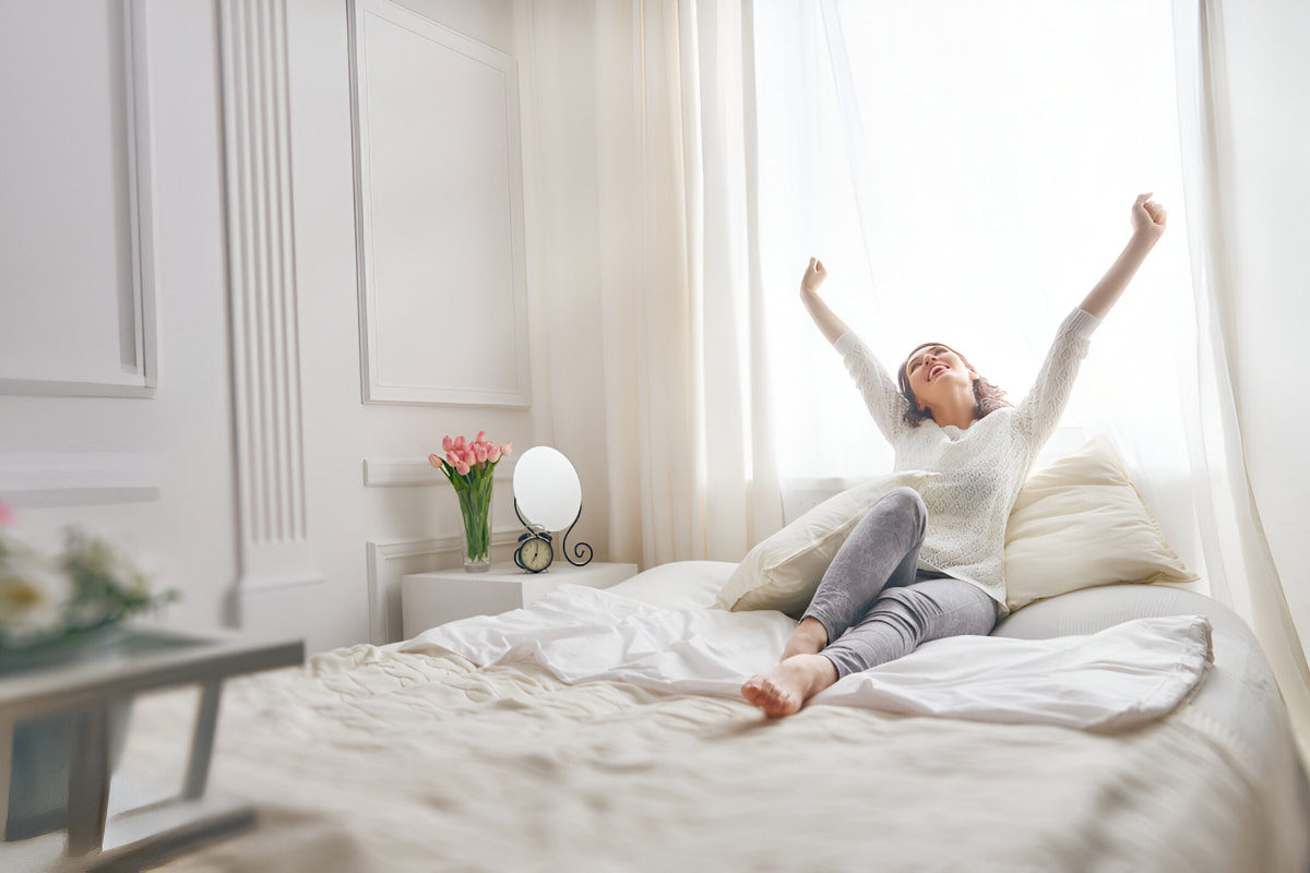 woman stretching on the bed after restful night's sleep