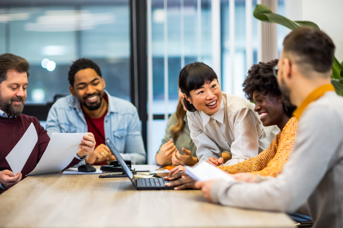 Multiethnic colleagues sitting around laptop at neuro-inclusive workplace